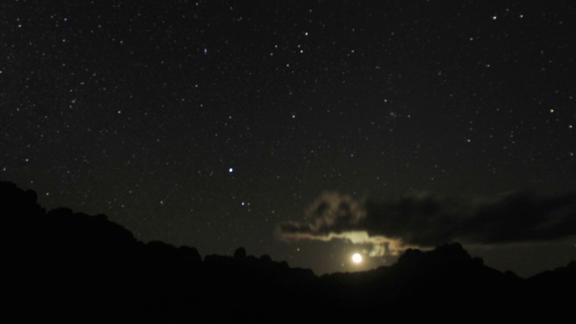 星星和月亮在夜晚的天空落在岩石山脊后，安德林吉拉，马达加斯加视频素材