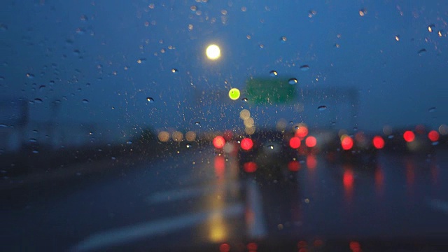 在黄昏下着雨的高速公路上开车，聚焦在车架上。视频素材