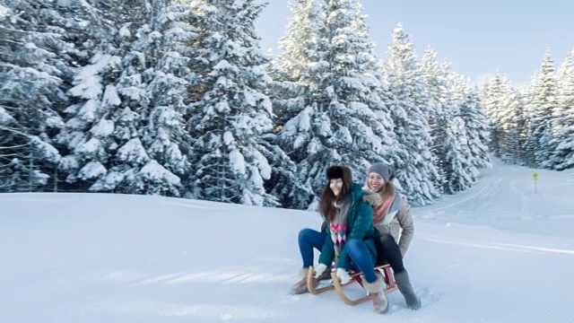 两个年轻女人在雪地上玩雪橇视频素材