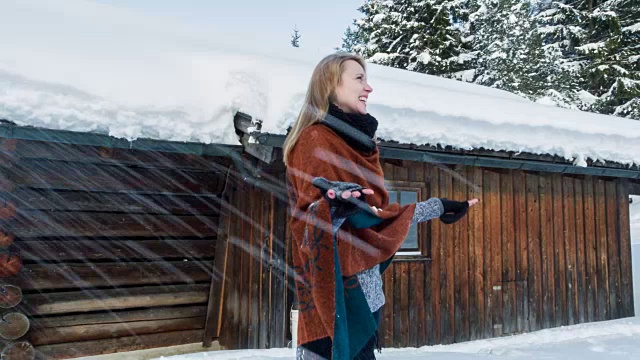 一名年轻女子在冬天向一间小木屋扔雪视频素材