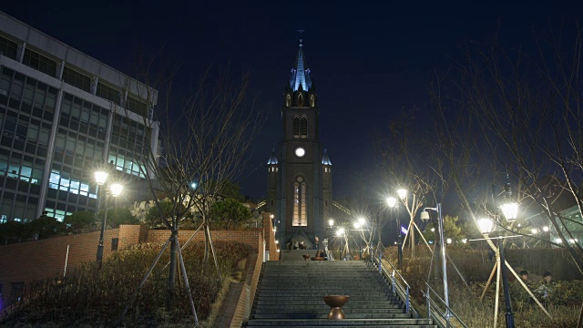 人们在明洞大教堂的台阶上上下走动的夜景视频素材