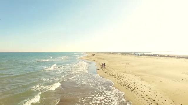 在加泰罗尼亚地区旅行的周末，一对直男情侣在地中海和低浪的埃布罗三角洲海滩上散步，用无人机拍摄了这段视频。4 k UHD。视频素材