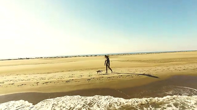 在加泰罗尼亚地区的周末旅行中，一名女孩在地中海和低浪的埃布罗三角洲海滩上散步和玩狗的视频是用无人机拍摄的。4 k UHD。视频素材