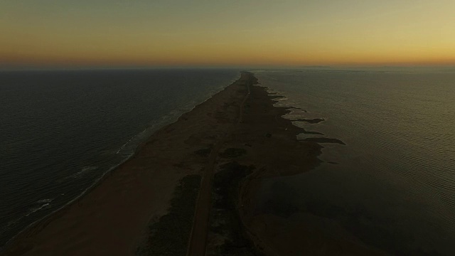 在日落时分，无人机在加泰罗尼亚地区的海滩和平坦的风景中，飞越埃布罗三角洲之间那片令人惊叹的狭长土地。4 k UHD。视频素材