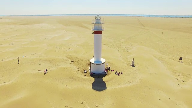 无人机在埃布罗三角洲美丽的海滩上空拍摄的航拍镜头，美丽的沙丘形成，白色的灯塔出现在加泰罗尼亚地区的沙漠中部。4 k UHD。视频素材