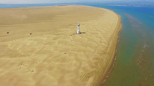 无人机在埃布罗三角洲美丽的海滩上空拍摄的航拍镜头，美丽的沙丘形成，白色的灯塔出现在加泰罗尼亚地区的沙漠中部。4 k UHD。视频素材