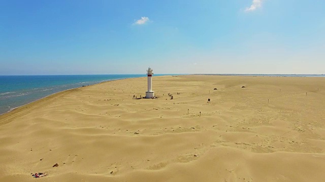 无人机在埃布罗三角洲美丽的海滩上空拍摄的航拍镜头，美丽的沙丘形成，白色的灯塔出现在加泰罗尼亚地区的沙漠中部。4 k UHD。视频素材