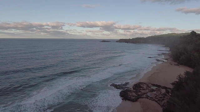 天线。当镜头飞回风景优美的海边山顶时，海浪在美丽的夏威夷海滩上拍打。视频素材