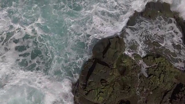 天线。俯视，海水溢出和撞击岩石岛海岸。视频素材