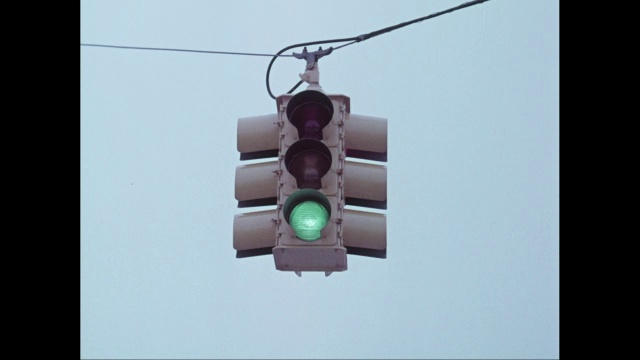 在晴朗的天空下，红绿灯悬挂在街道上视频素材