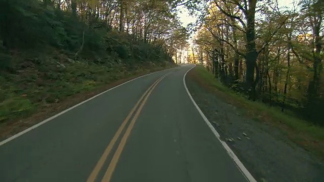 在有秋叶的乡村道路上风景优美的驾驶。视频素材