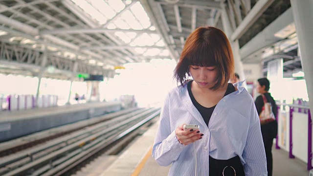 一名女子在火车站使用智能手机视频素材