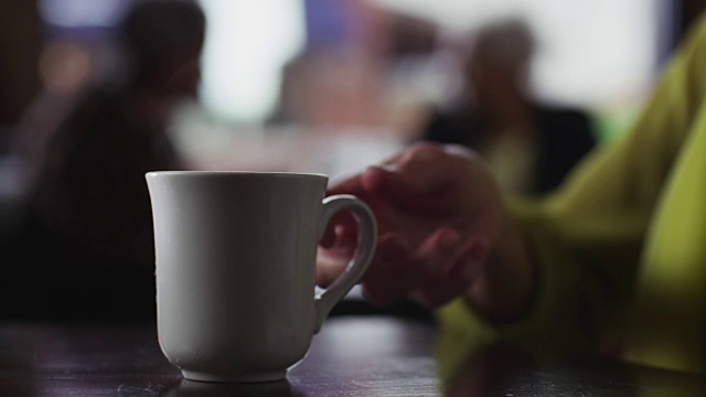 近距离的陶瓷咖啡杯是一个女人捡起在咖啡店。视频素材