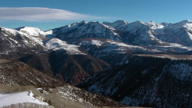 在蓝天的映衬下，雪花攀附在山坡和山峰上。视频素材