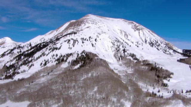 在蓝天的映衬下，雪花攀附在山坡和山峰上。视频素材