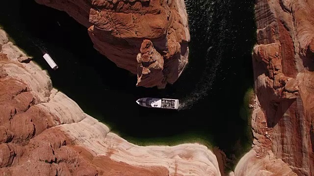 在鲍威尔湖上航行的狭窄水道拉起，无人机鸟瞰在鲍威尔湖水库和科罗拉多河上的皮艇和船，美丽的沙石形成和水反射位于格伦峡谷，亚利桑那州视频素材