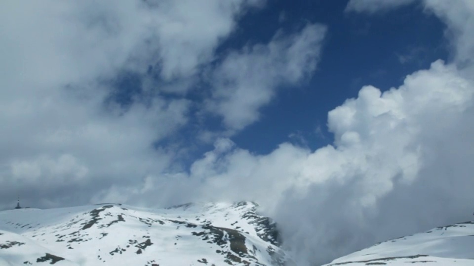 乌云在白雪皑皑的山顶上翻滚。视频素材