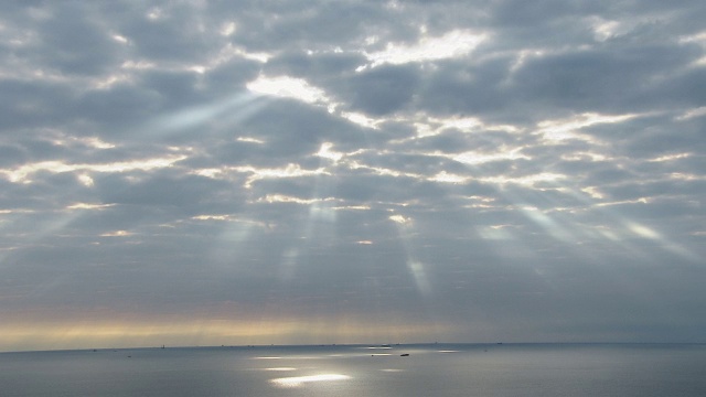 太阳穿过云层照在散布在海上的船只上。视频素材