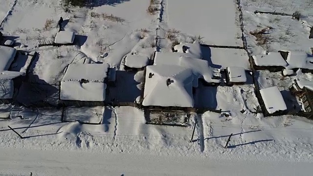 一个典型的西伯利亚村庄。冬天。房顶上有很多雪。传统的俄罗斯木屋是小屋。视频素材