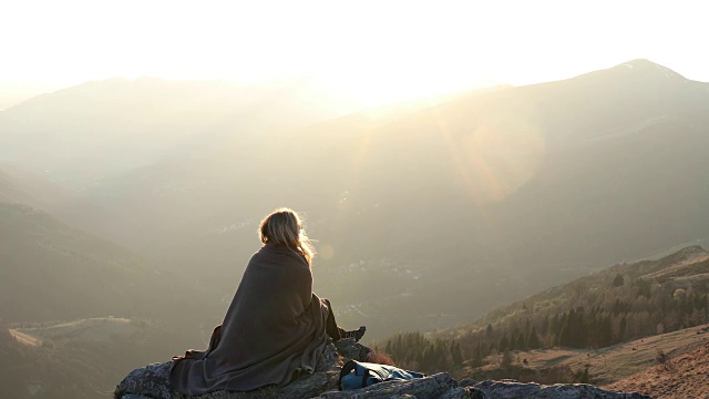 女性徒步旅行者在山顶上放松，穿着毯子视频素材