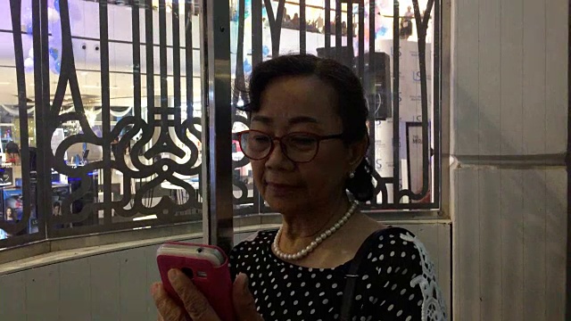 一位年长女性在电梯里使用智能手机视频素材