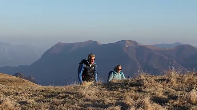 一对徒步旅行的夫妇向山顶跋涉，看那边视频素材