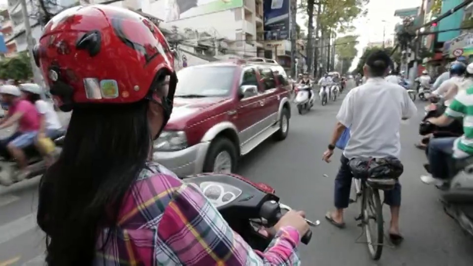 一个女人开着摩托车穿过混乱拥挤的交通。视频下载