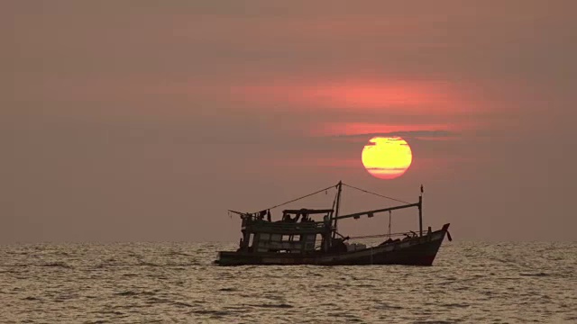 一艘渔船驶过夕阳下的海面视频素材