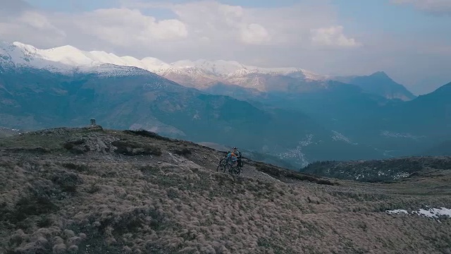 山地车在雪山下攀登山脊的鸟瞰图视频素材