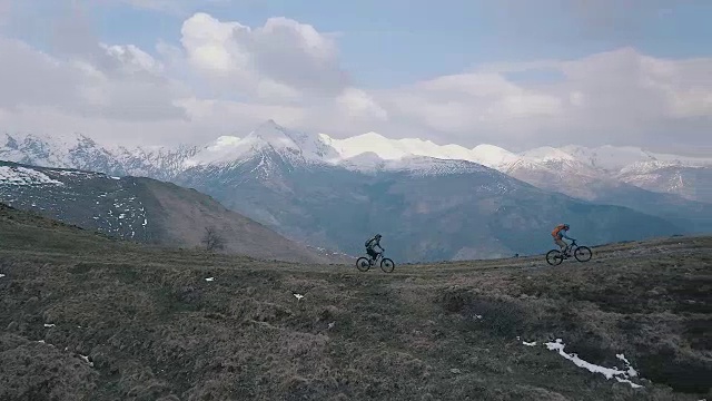 鸟瞰图的山地自行车下降的山脊下的雪山视频素材