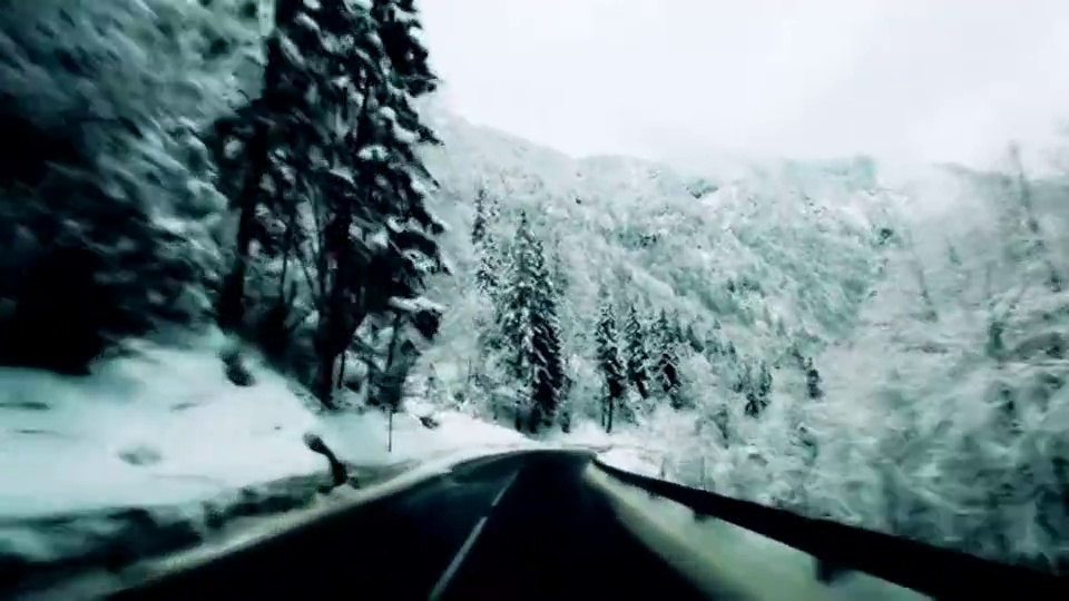 一辆汽车在树木环绕的雪道上行驶。视频下载