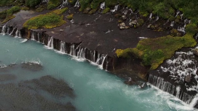 宽高角度平移拍摄瀑布倾泻到河/ Hraunfossar，冰岛视频素材