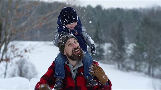 父亲和儿子在冬天暴风雪的户外玩耍视频素材