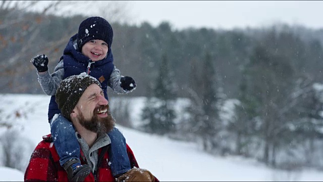 父亲和儿子在冬天暴风雪的户外玩耍视频素材