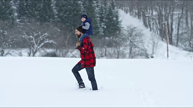 父亲和儿子在冬天暴风雪的户外玩耍视频素材