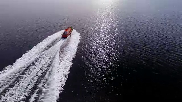 航拍照片，一艘领航船在平静的海面上疾驰，迎接它的船只进入航运码头。视频素材