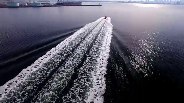 这是一艘领航船在平静的海面上疾驰，迎接它的船只进入航运码头的反向航拍照片。视频素材