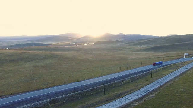 航拍的道路延伸到遥远的地平线上的草原在日落，中国甘肃。视频素材