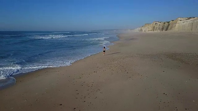 女人沿着海滩慢跑后视图视频素材