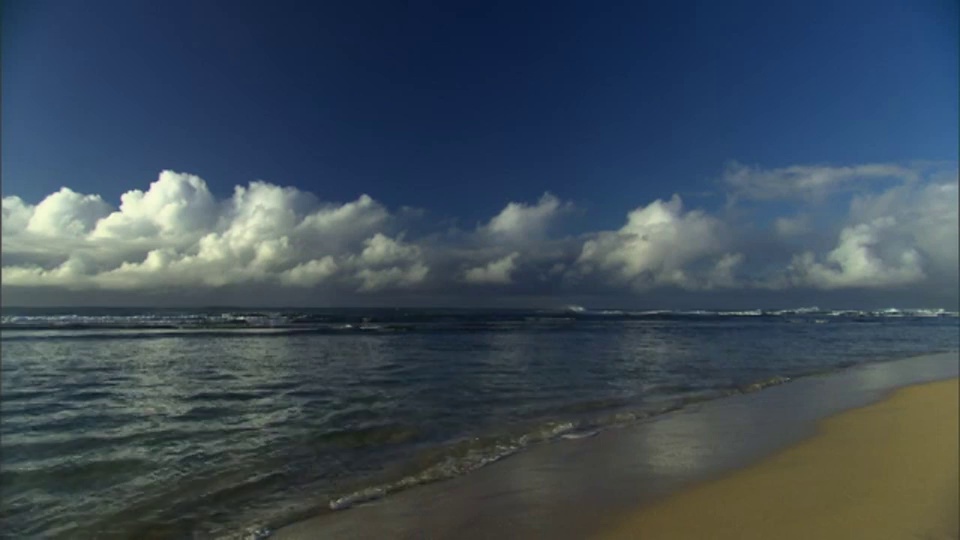 海浪轻轻拍打在荒芜的海滩上。视频素材