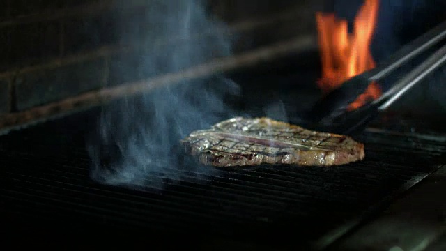 t骨牛排肉在烧烤烤架上烹饪视频素材