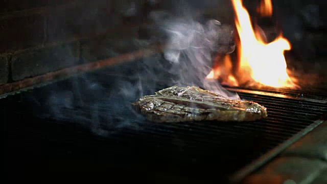 t骨牛排肉在烧烤烤架上烹饪视频素材