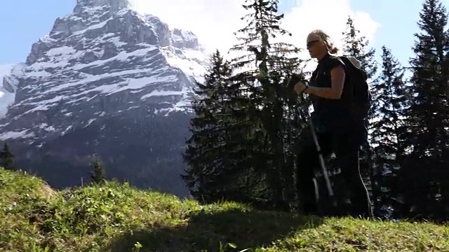 女徒步旅行者穿过雪山下的草地视频素材