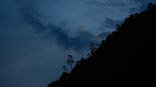 月亮落在树和山的剪影后面视频素材