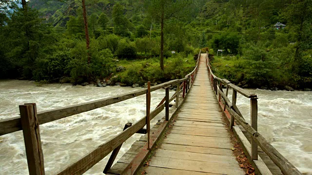 摇摇欲坠的木桥横跨湍急的河流，位于喜马拉雅山的马纳里地区视频素材