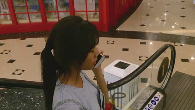 年轻女子在自动扶梯上使用智能手机视频素材