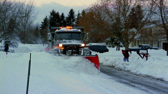 中型射击大型卡车在郊区街道上铲雪视频素材