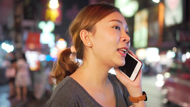 亚洲女孩在夜城的街道上使用手机视频素材