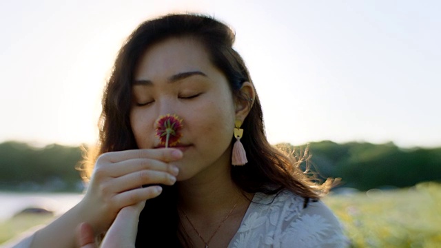 女孩闻着花香，在神奇的时刻将花拿在手里旋转。视频素材