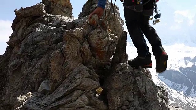 一名男性登山运动员攀登雪山之上的岩石山脊视频素材